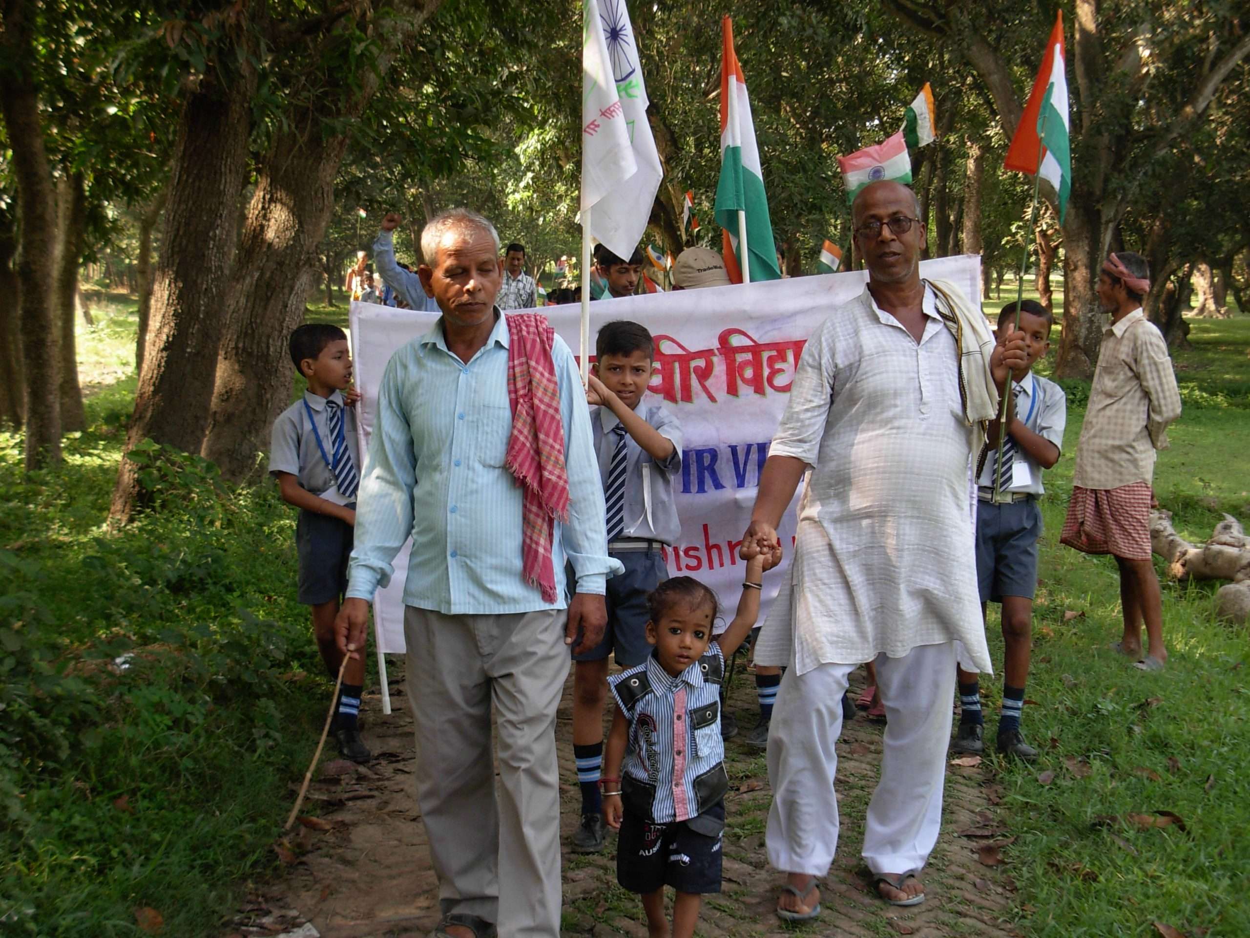 Community freedom march led by Trust members with Indian tricolor flags, walking through fields