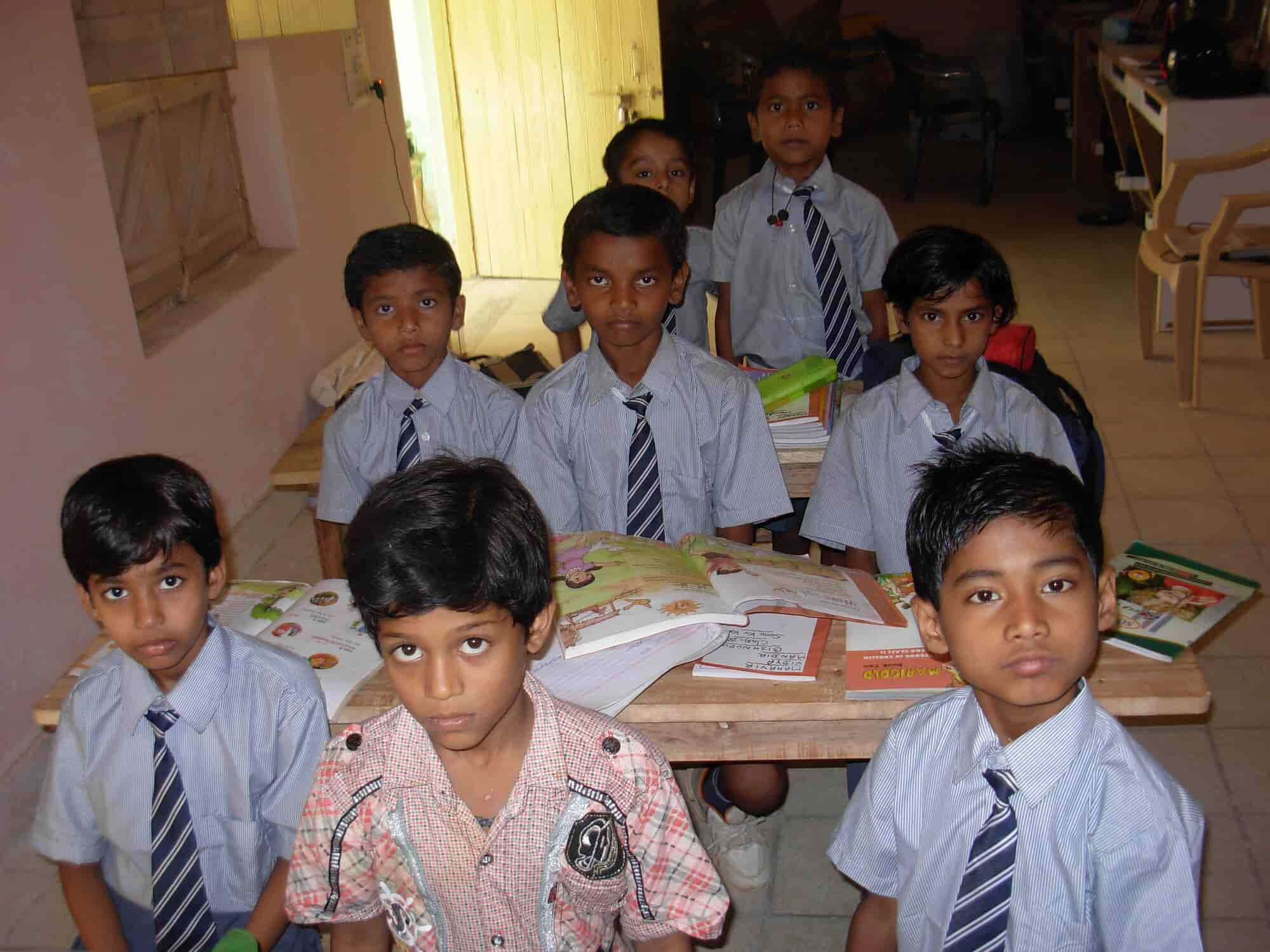 Boys in school uniform gathered around a wooden classroom table with books open
