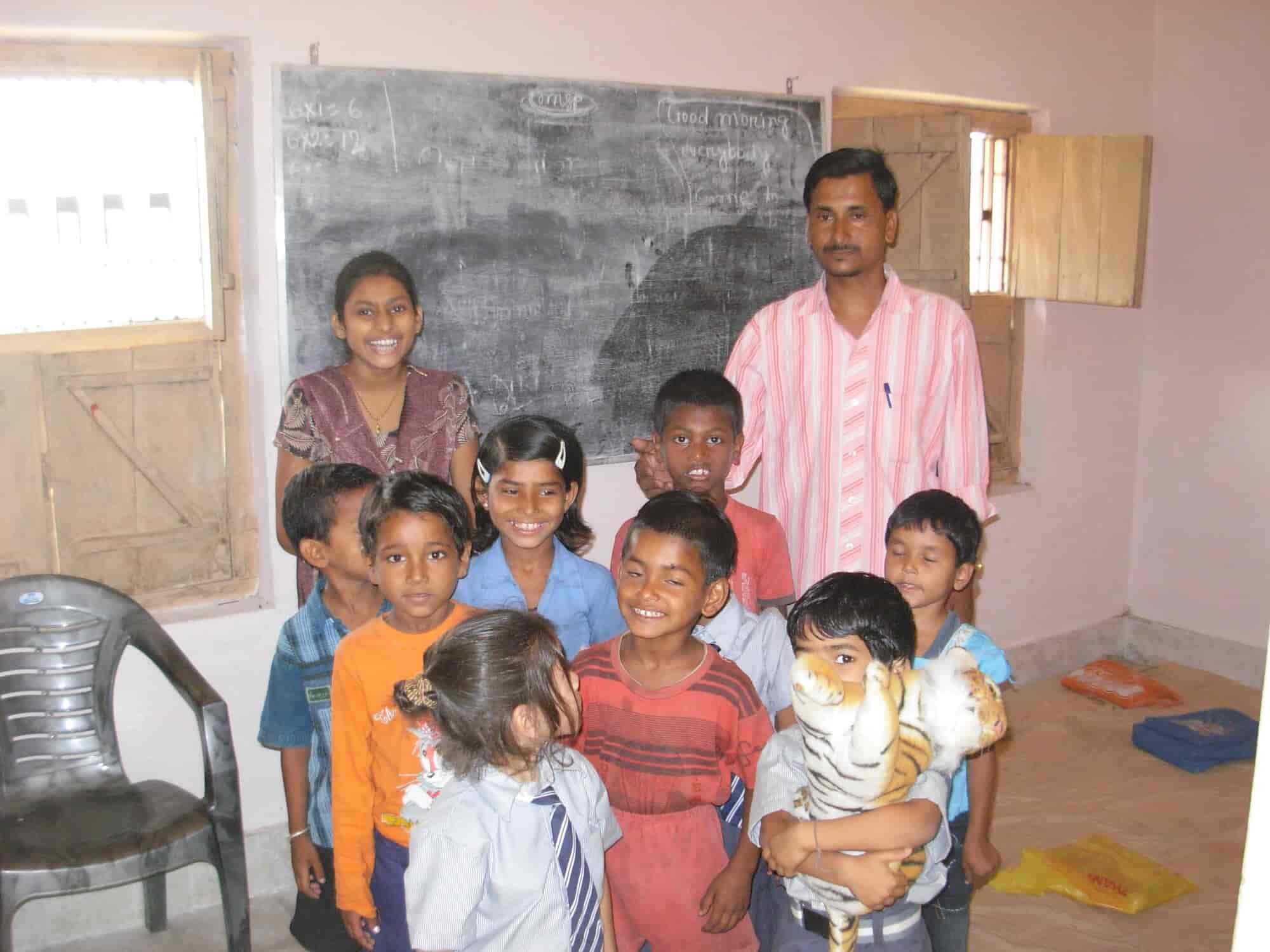 Group of children in a classroom with teacher behind, one boy holding a stuffed tiger toy