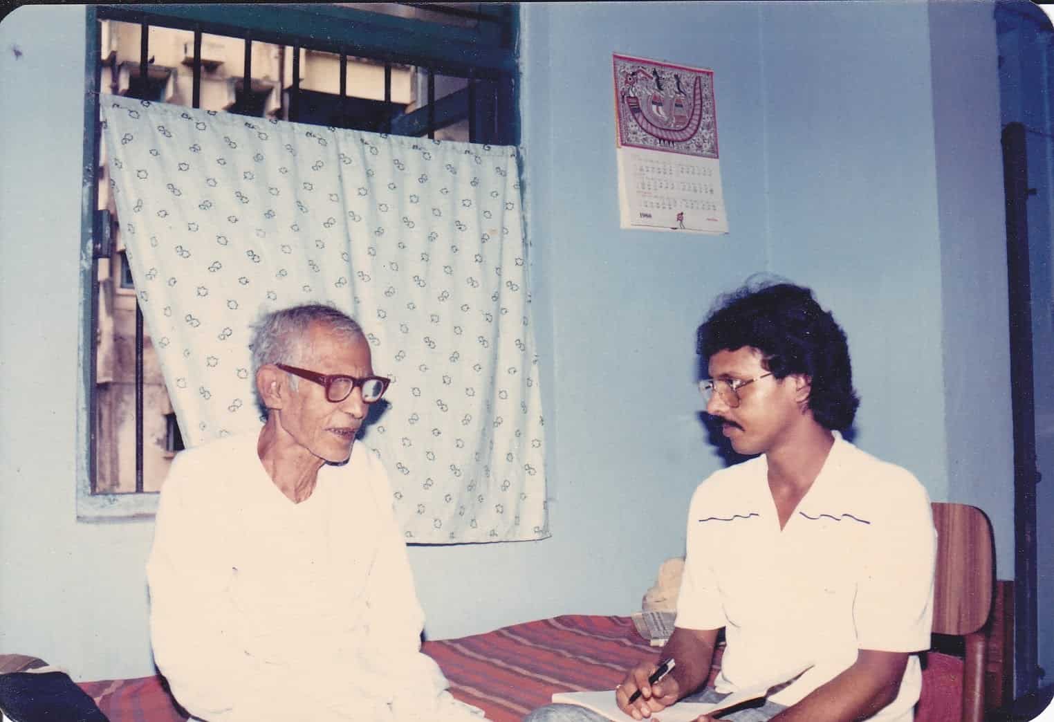 Mahavir Singh in his later years being interviewed by a young man taking notes, c. 1988
