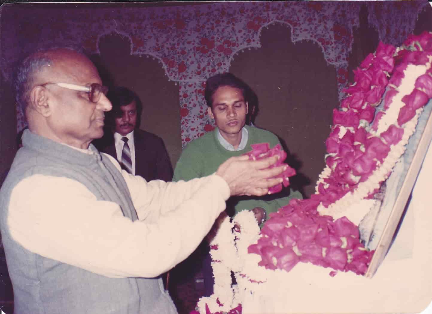 Trust member placing rose-petal garland on a framed portrait of Mahavir Singh, founding ceremony December 1992