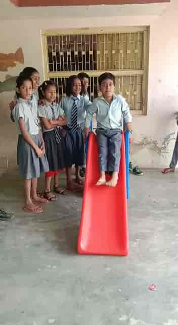 Children gathered around a red plastic slide in the school playground area