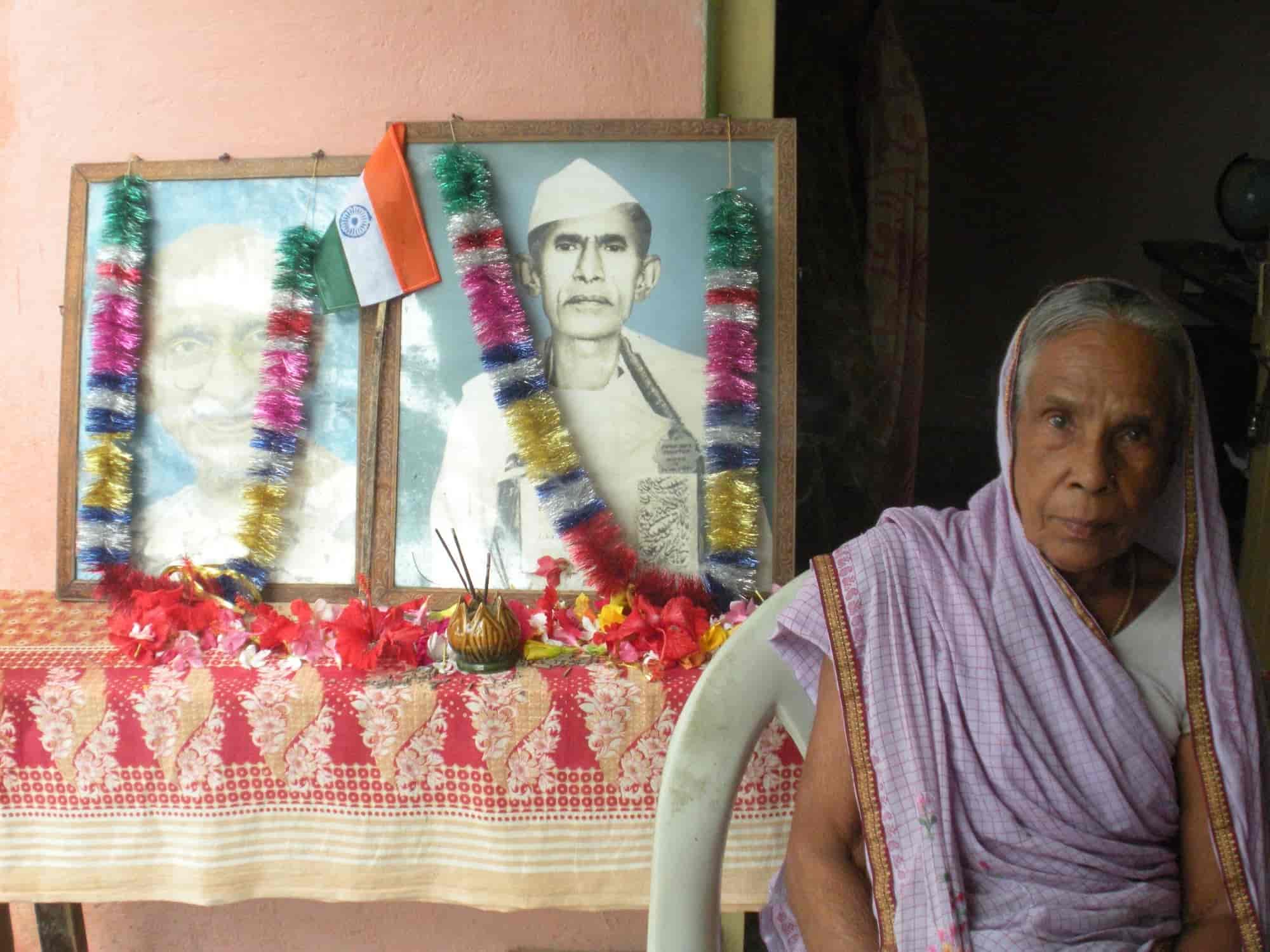 Garlanded framed portraits of Mahatma Gandhi and Mahavir Singh with tricolor flag, his widow seated alongside