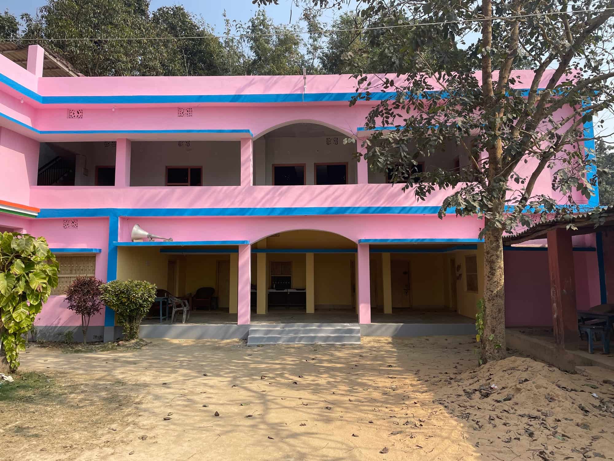 The pink Trust building's central courtyard with arches, chairs and a loudspeaker