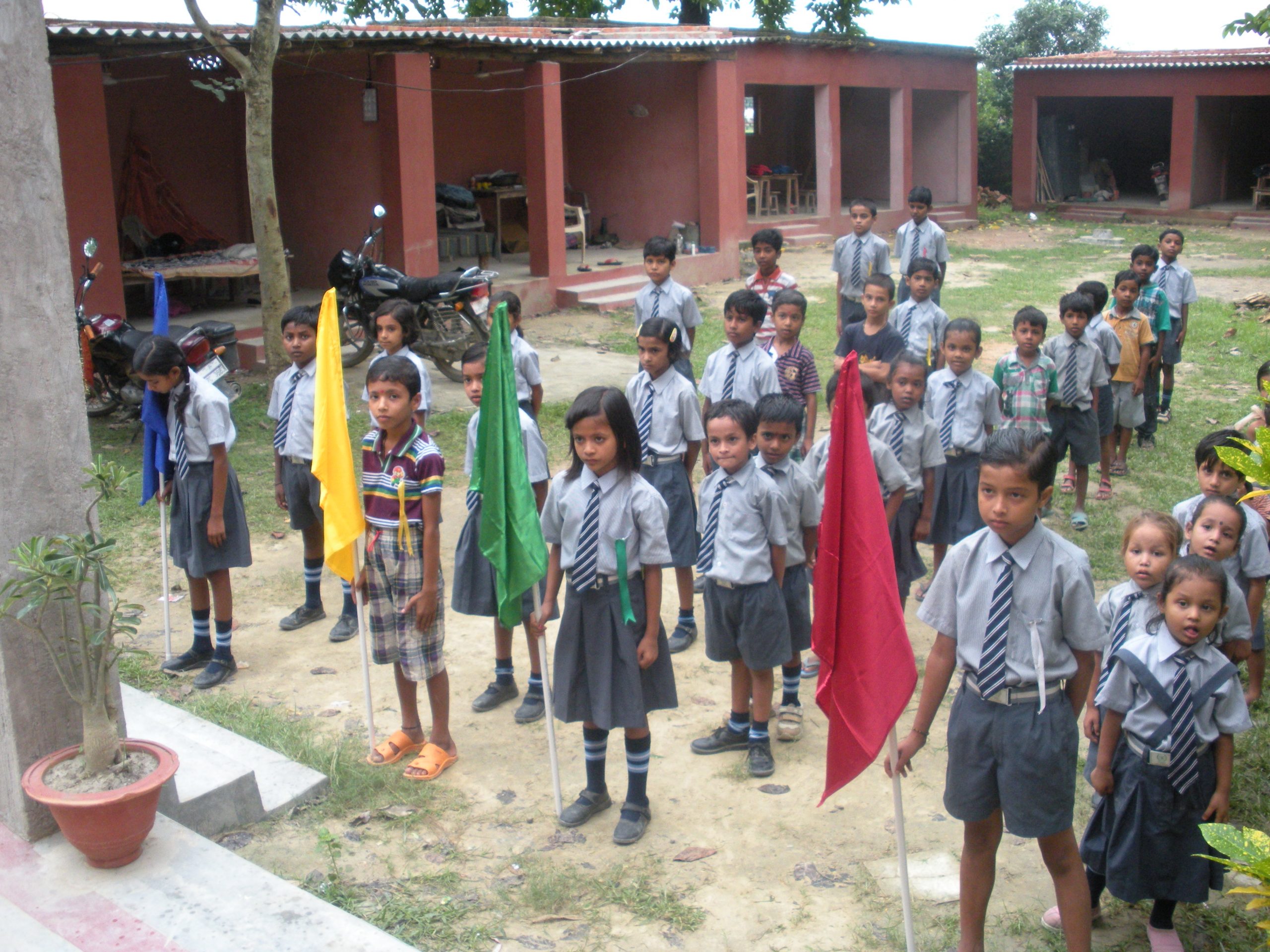 Children at Mahavir Vidya Mandir gathered with flags in their school courtyard